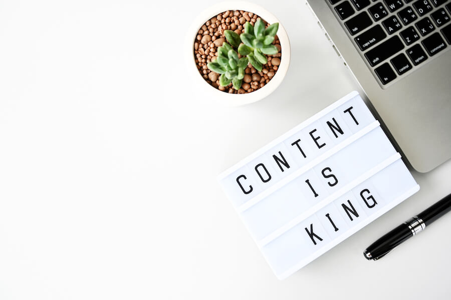 nápis Content is king na světelné tabulce vedle notebooku